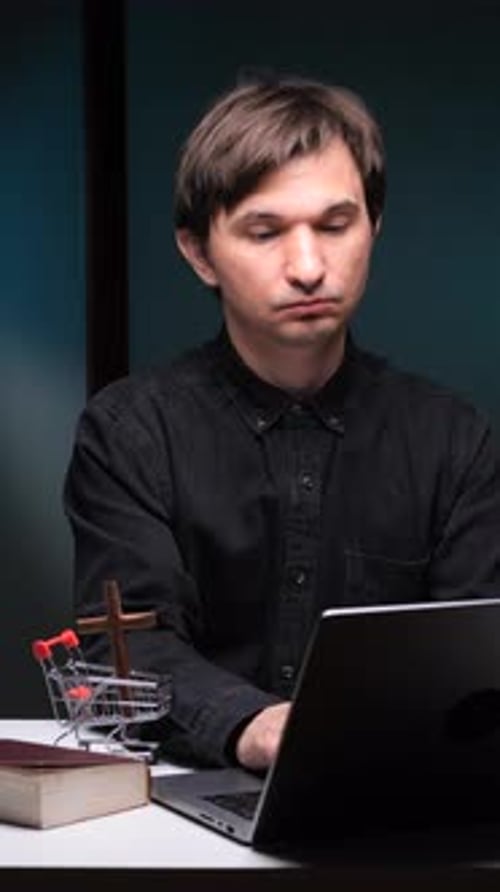 Adult Typing on Laptop with Cross and Book