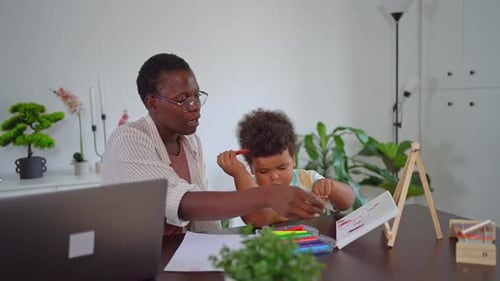 Woman and Child Drawing Together at Table Indoors