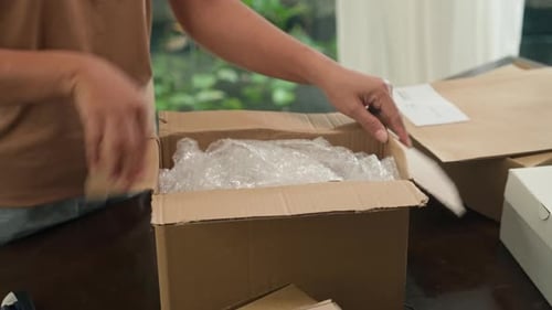 Woman opens a shipping box and removes a glass vase