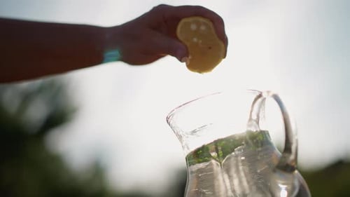 Refreshing Lemonade: Hand Squeezing Lemon into Pitcher