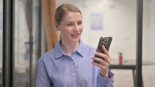 Woman Using Smartphone for Video Call in Office