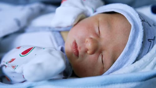 Lovely Caucasian newborn kid’s face. Sleeping infant few days old close up portrait.