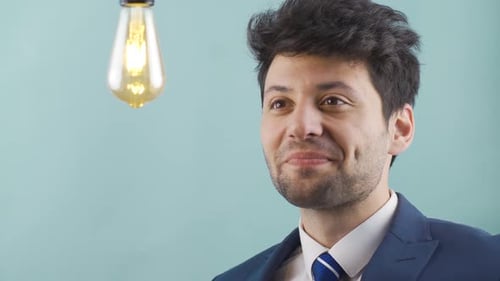 Thoughtful businessman comes up with a new idea and the idea lamp lights up.