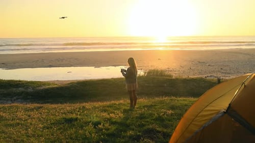Woman pilot drone at beach, sunset and quadcopter flight at sea, spy or surveillance on summer