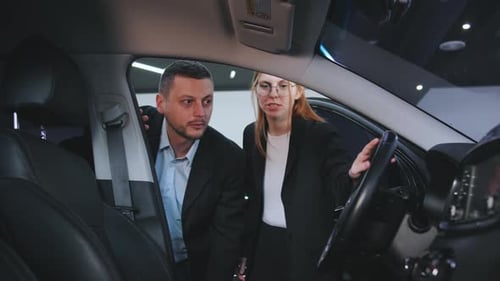 Salesperson Demonstrates Car Features to Potential Buyer in a Modern Showroom Setting During