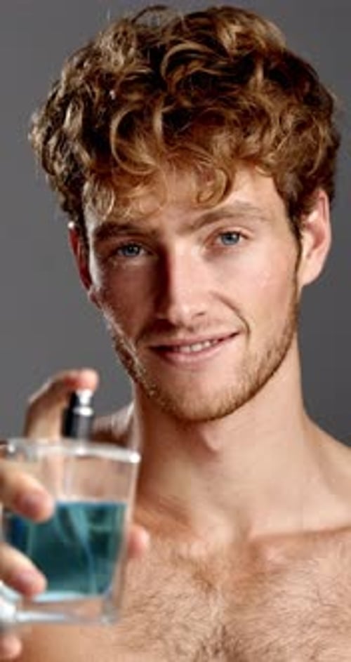 Spray cologne, face and smile of man in studio for fresh aroma, grooming or hygiene product