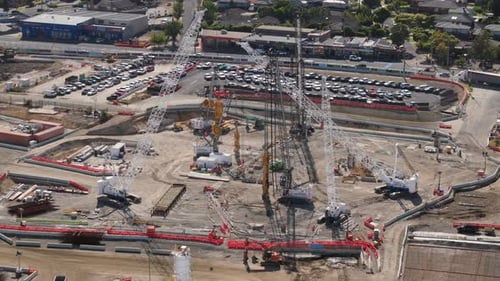Pase aéreo por grandes grúas inmóviles en un sitio de construcción suburbano