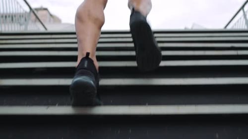 Fit man running and jogging up steps on a bridge in the city outdoors
