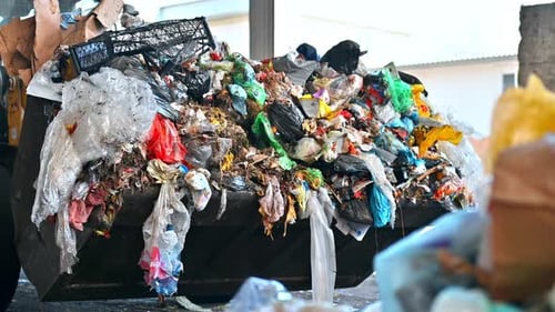 An excavator carries garbage at waste sorting plant. Slow motion
