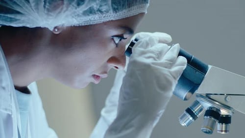 Young Adult Scientist Examining Sample Under Microscope