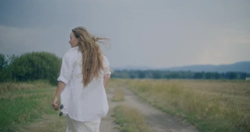 Young Woman Looking Away While Walking In Field