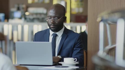 Black Man Working on Laptop in Restaurant