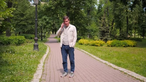 A Man is Talking on the Phone on the Street A Guy in a Jacket Makes a Call