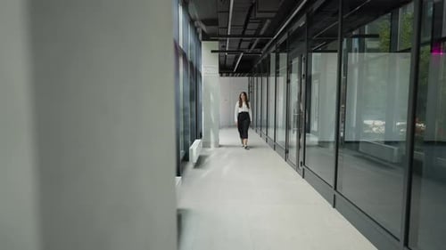 A Woman Walks Along the Corridor of a Business Center