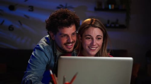 Happy Couple Watching Laptop at Night Indoors
