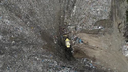 Bulldozer pushing waste in a garbage huge landfill - aerial view