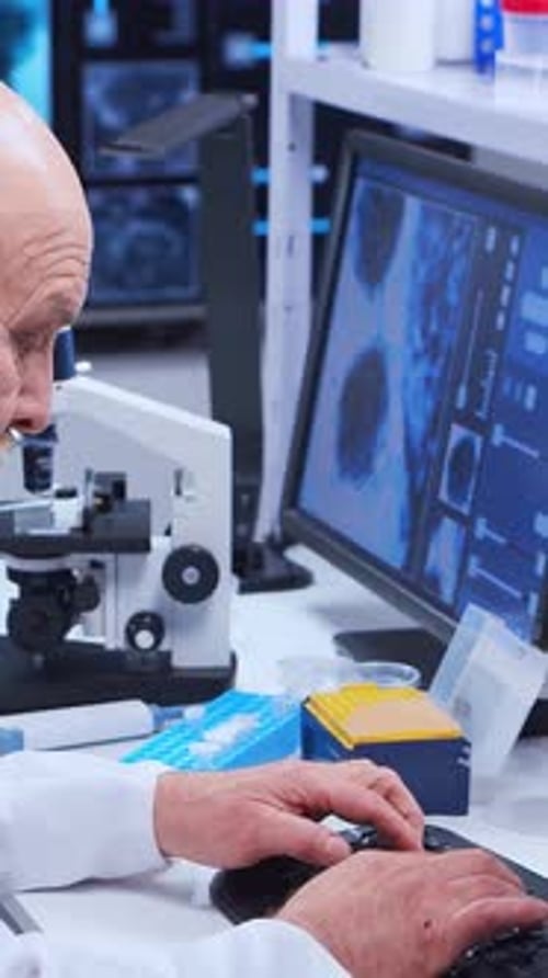 Older Researcher Typing at Computer in Bright Lab