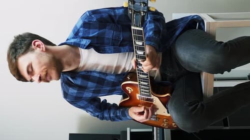 Man Plays Electric Guitar Indoors During the Day