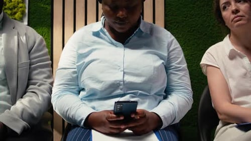 Relaxed Female Applicant Browses Phone in Hallway Lineup and Waiting