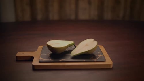 A Beautifully Sliced Pear is Placed Artfully on a Wellused Wooden Cutting Board