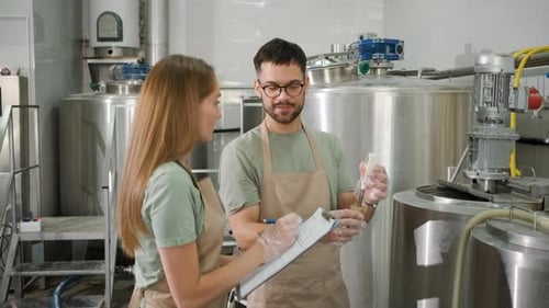 Homme et femme travaillant dans une brasserie artisanale vérifiant le pH de la bière.