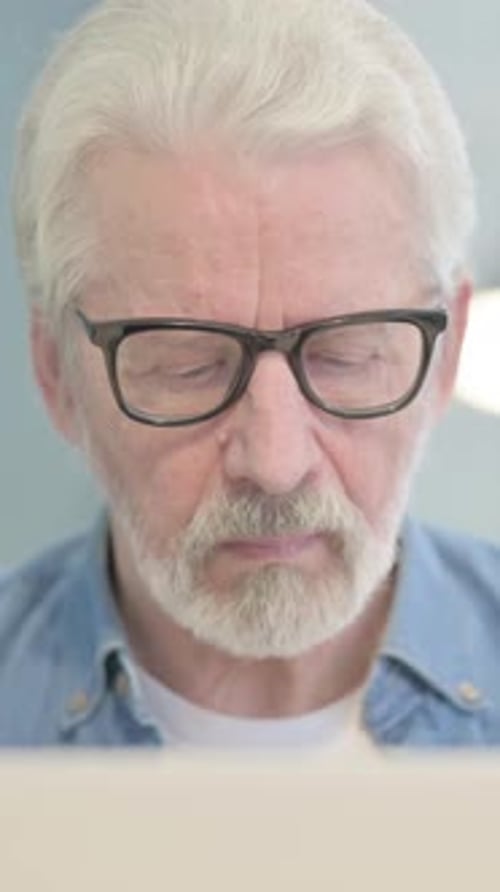 Close Up of Old Man Looking at Camera while using Laptop, vertical video