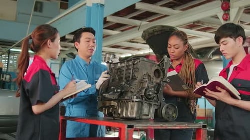 Der Supervisor-Ingenieur bringt Mechanikern in einer Werkstatt etwas über Automotoren bei.