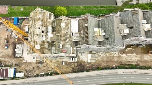 Vista aérea de un sitio de construcción con edificios en desarrollo, cubiertos de andamios, y un c