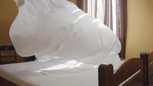 Female Housekeeper Changing Bedding in a Hotel Room