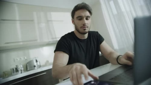 Man Working on Laptop and Talking on Phone