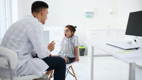 Doctor Examining a Young Child's Throat in Clinic