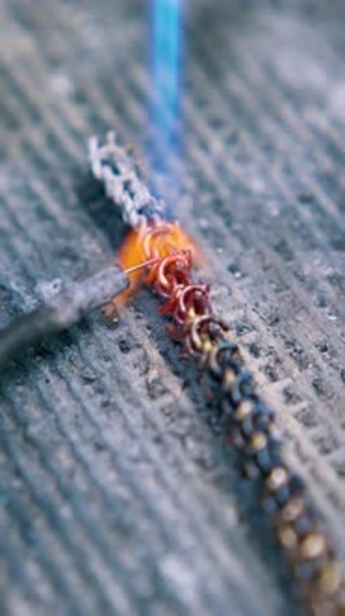Jeweler Works with Metal Chain Using Gas Burner Close View