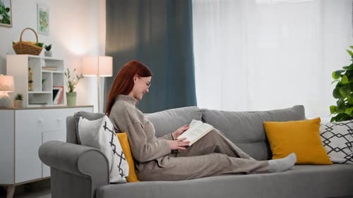 Woman Relaxing on Couch Reading Book at Home