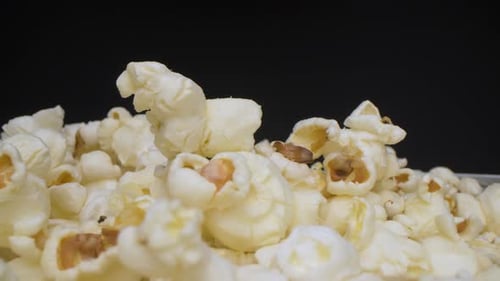 Close-up view of buttered popcorns falling into the bowl. Preparing for evening.