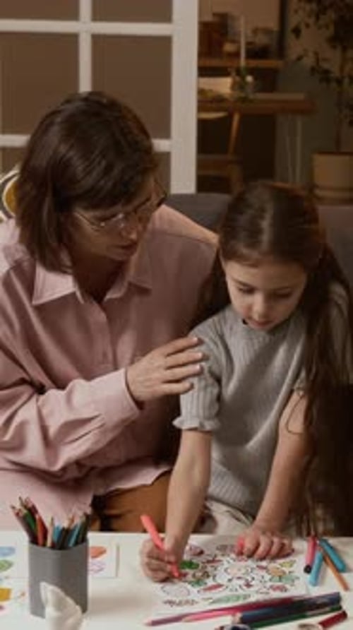 Vertical of Grandmother Helping Little Granddaughters Coloring Easter Drawings