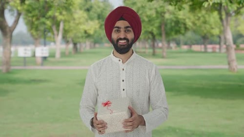 Happy Sikh Indian man receiving a gift in park