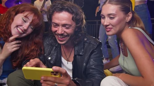 Friends Laughing Together Watching a Yellow Smartphone