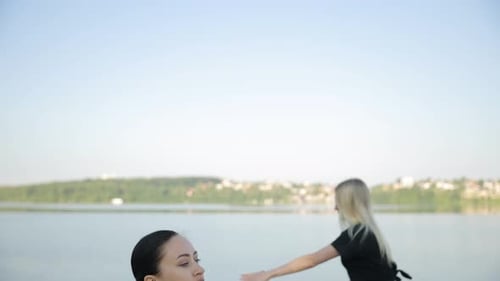 Women in Sportswear Doing Sports Exercises Outdoors Near the Lake