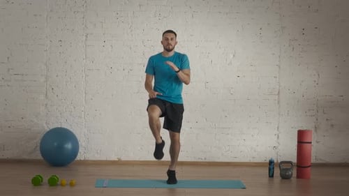 Man Fitness Coach in Sportswear Doing High Knee Jumps in Place for Online Class at the Home Studio