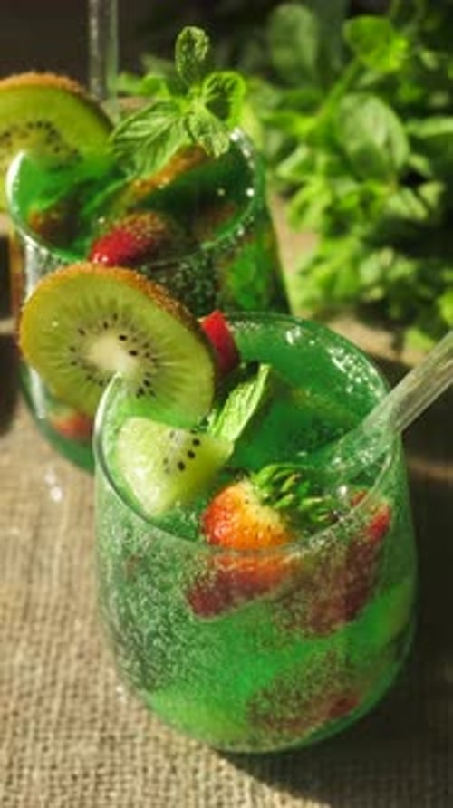 Vertical Screen Two Thin Glass Glasses Filled with a Refreshing Fizzy Drink and Fresh Pieces of Kiwi