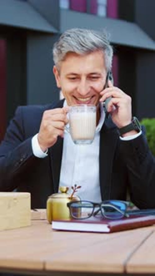 Man in Suit Talking on Phone and Drinking Coffee