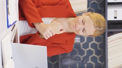 Woman experiencing wrist pain at work on laptop