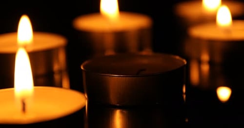 Burning tealight candles in the darkness close-up