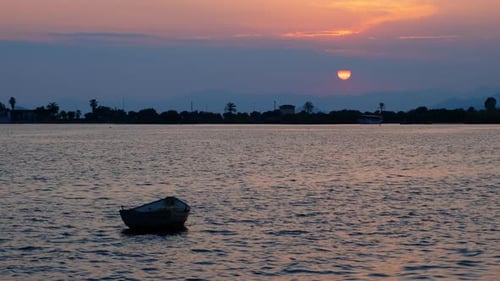 Peaceful Sunset over Water with Small Boat
