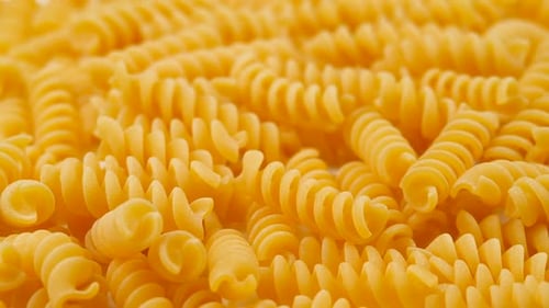 Pile of Yellow Dried Rotini Pasta Close Up