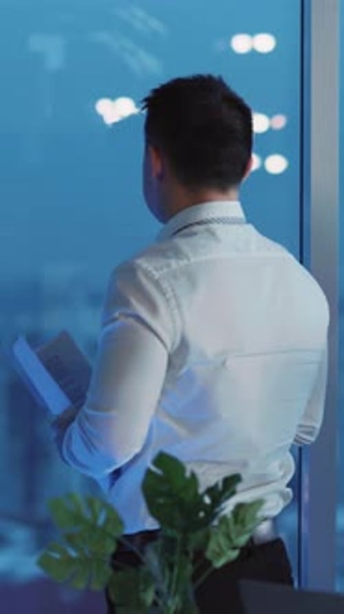Adult Looks Out Office Window at Night