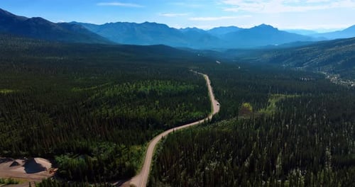 Aerial View of Road Through Forest and Mountains