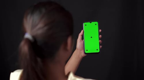 Woman holding smartphone watching touching and swiping content on chroma key green screen smartphone