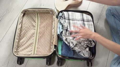 Man packing his suitcase for long journey with wad of money. Guy closes the green baggage case