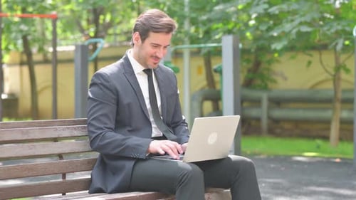 Young Adult in Suit on Laptop Celebrates Success
